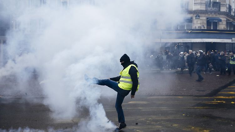 Ein Demonstrant wirft einen Tränengasbehälter während einer Demonstration der "Gelbwesten" weg.