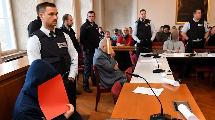 Der angeklagte Vater wird zusammen mit seinen Söhnen von Justizwachtmeistern bewacht.