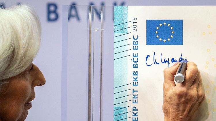 EZB-Chefin Christine Lagarde unterschreibt symbolisch einen übergroßen 20-Euro-Schein.