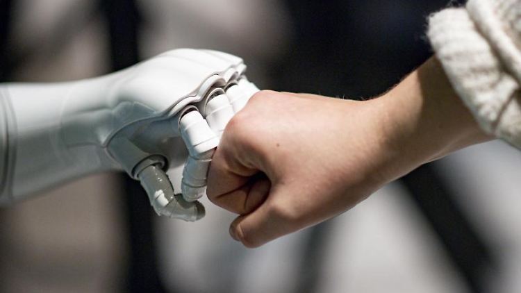 Ein Roboter interagiert mit einer Frau. Foto: Axel Heimken/dpa/Archivbild