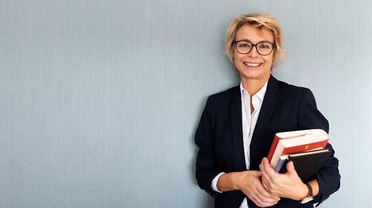 Dass die Dame kompetent wirkt, liegt nicht nur am Bücherstapel. Das Gehirn bewertet zuerst ihre Kleidung.