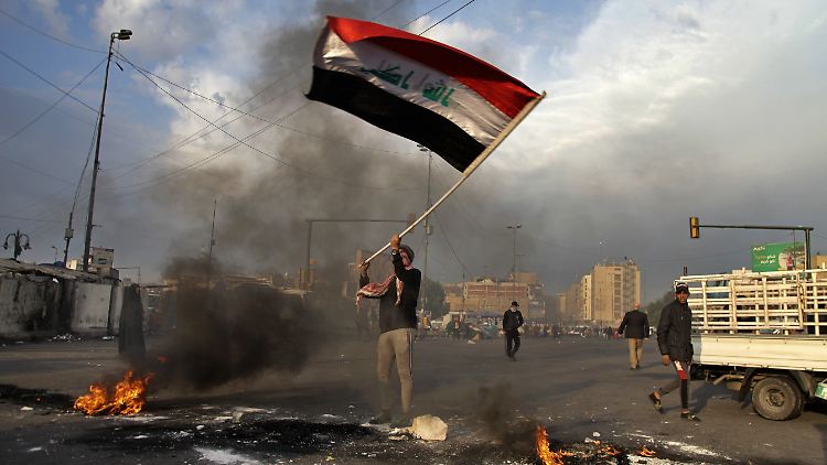 Nach den Raketenangriffen des Iran schwenkt ein Iraker aus Protest in Bagdad die irakische Flagge.