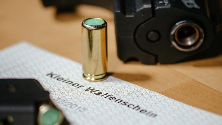 Eine Schreckschusspistole mit einem kleinen Waffenschein. Foto: Oliver Killig/zb/dpa/Symbolbild