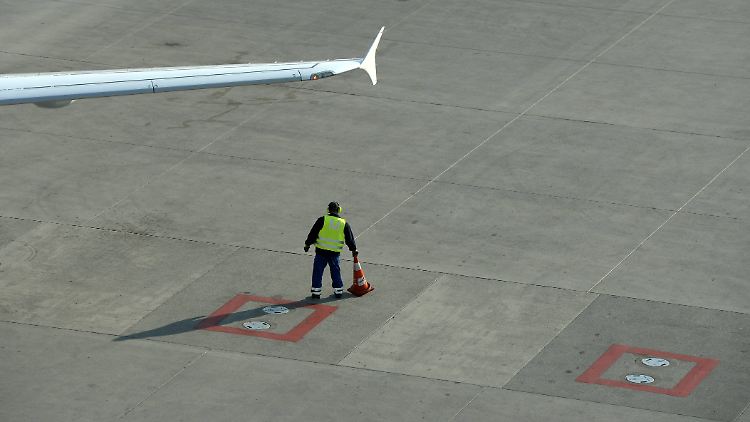 Ein Mitarbeiter positioniert eine Begrenzung neben einem geparkten Flugzeug.