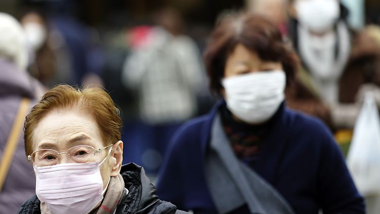 Fußgänger in Tokio schützen sich vor Infektionen mit einem Mundschutz. Ein Patient in Japan wurde positiv auf das Corona-Virus getestet.