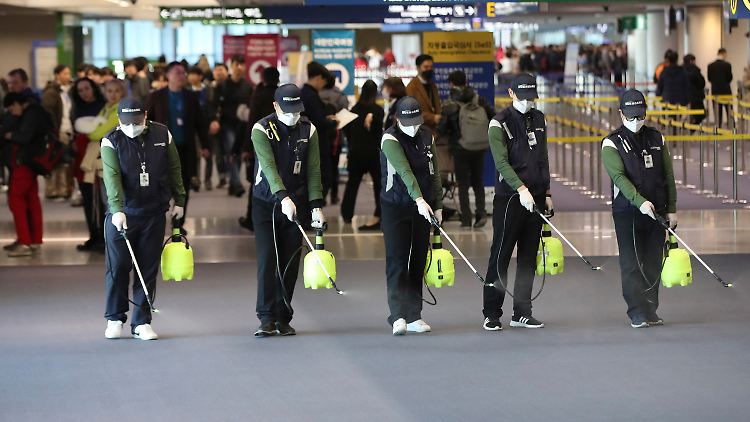 Flughafenpersonal versprüht in der Ankunftshalle am Flughafen im südkoreanischen Incheon eine keimtötende Lösung - eine Schutzmaßnahme gegen die Verbreitung des Corona-Virus.