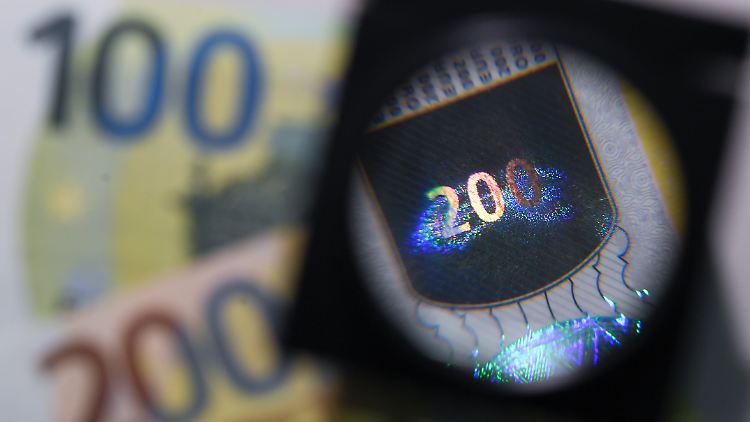 Eine Lupe gibt den Blick auf das neue "Satelliten-Hologramm" einer überarbeiteten 200-Euro-Banknote frei.