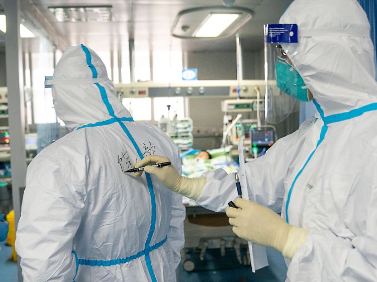 Arbeiten unter erschwerten Bedingungen: Mit einem Filzstift notiert das medizinische Personal in einem Krankenhaus in Wuhan den Namen eines Kollegen auf dessen Rücken.