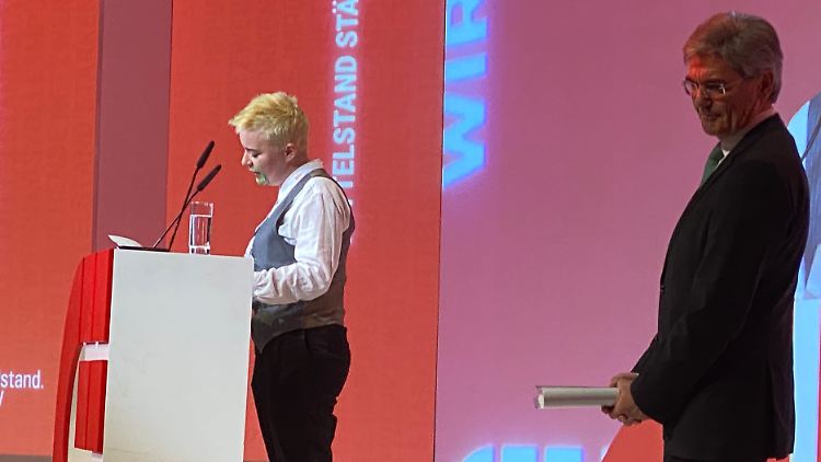 Die Aktivistin stand so lange auf der Bühne, bis ein Sicherheitsmitarbeiter sie herunter begleitete.