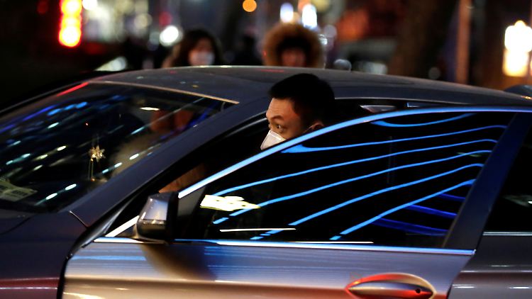Straßenszene in Peking: Passanten und Autofahrer versuchen sich per Mundschutz vor dem ansteckenden Coronavirus zu schützen.