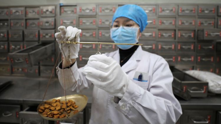 Eine Apothekerin wiegt Pflanzenteile ab, die der Traditionellen Chinesischen Medizin zugeordnet werden und bei einer Infektion mit den neuen Coronaviren helfen soll.