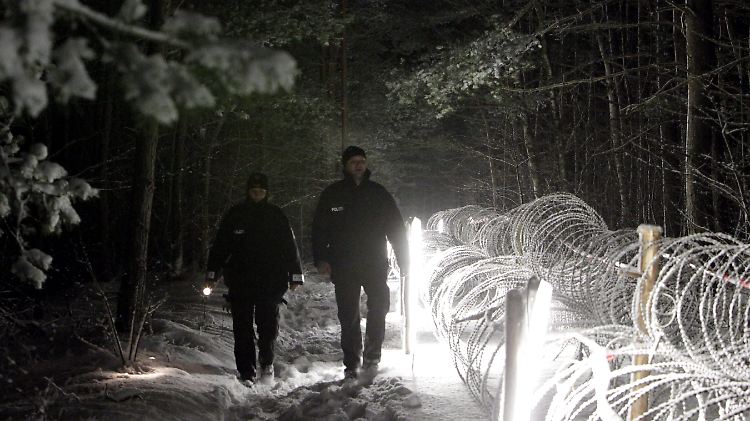 Castor-Transport im Winter: Zwei Beamte passieren auf ihrem Kontrollgang eine verschneite Polizeisperre.