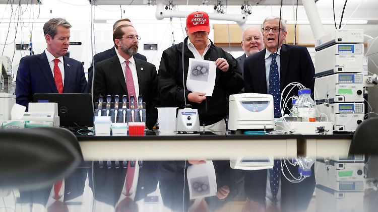 Ortstermin in der US-Seuchenkontrollzentrale CDC: US-Präsident Donald Trump trägt Wahlkampfkappe und zeigt ein ausgedrucktes Coronavirus-Bild vor.