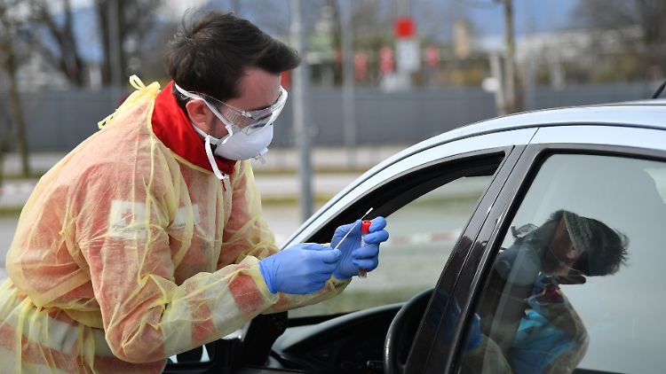 Ein Mitarbeiter der "Drive-in"-Teststation vom Roten Kreuz macht einen Coronavirus-Test bei einem Autofahrer in Salzburg.