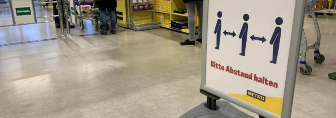 Ein Hinweisschild bittet die Kunden im Kassenbereich Abstand zum nächsten Kunden zu halten. Foto: Alexander Blum/dpa