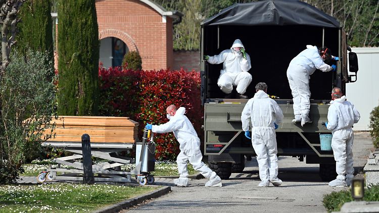 Im italienischen Ferrara bringen Männer in Schutzanzügen den Leichnam eines Corona-Kranken auf einen Friedhof.