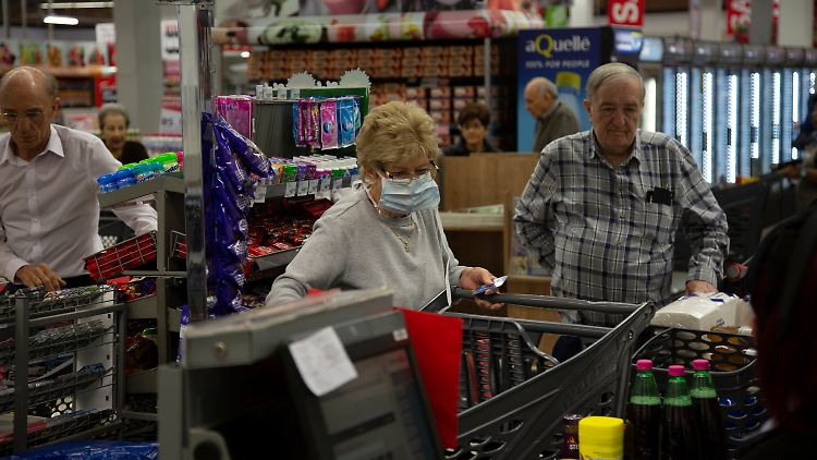 Eine Frau steht mit Atemmaske an eine Supermarktkasse in Johannesburg - dort droht das Virus eine Katastrophe auszulösen.