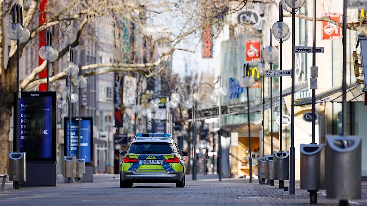 Ein Polizeiwagen fährt in Köln durch die menschenleere Schildergasse.