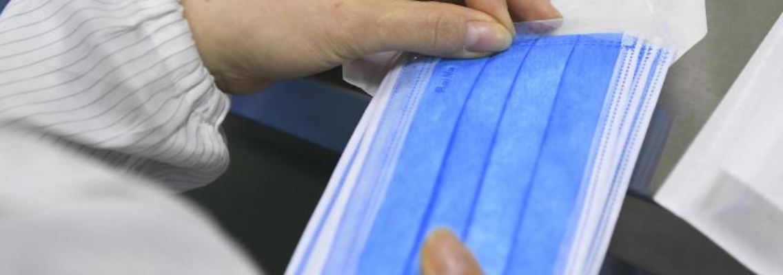 Ein Mitarbeiter verpackt Mundschutz-Masken. Foto: Wang Quanchao/XinHua/dpa/Symbolbild