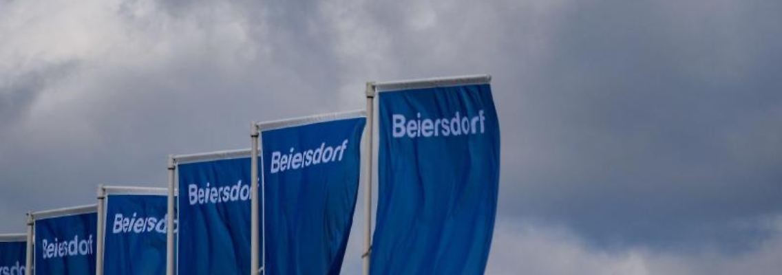 Fahnen der Beiersdorf AG wehen vor der Messe Hamburg. Foto: Axel Heimken/dpa/Archivbild