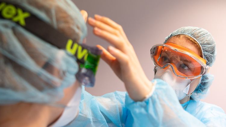 Mitarbeiterinnen einer Berliner Zahnarztpraxis beim Anlegen von Schutzkleidung.