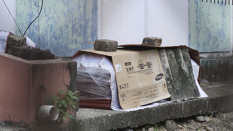 Ein notdürftig geschützter Sarg liegt vor einer Wohnung.