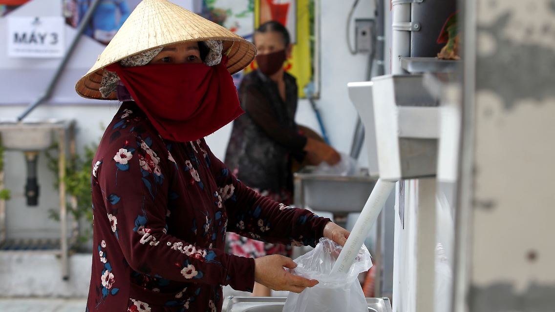 Eine Frau füllt sich Reis aus einem Automaten in Ho-Chi-Minh-Stadt ab.