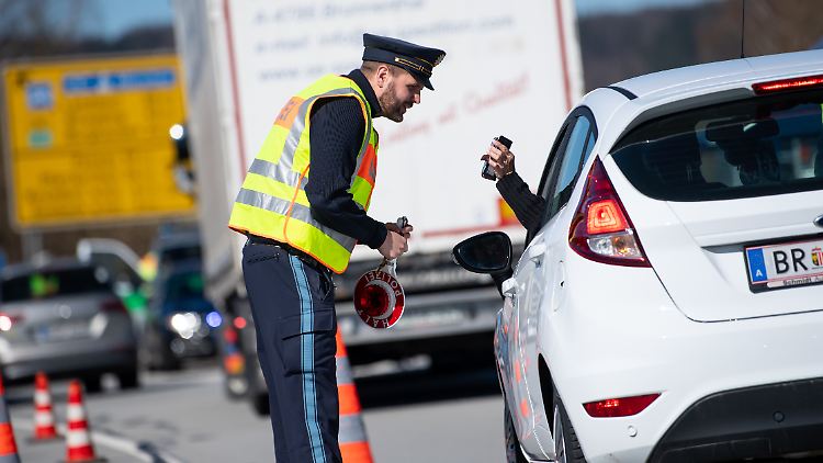 Ein Polizist überprüft einen Autofahrer an einem Grenzübergang zu Österreich. 