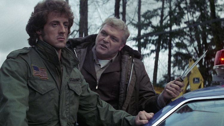 In "Rambo" macht der Sheriff (Dennehy, r.) Jagd auf Rambo (Stallone) - doch der wehrt sich.