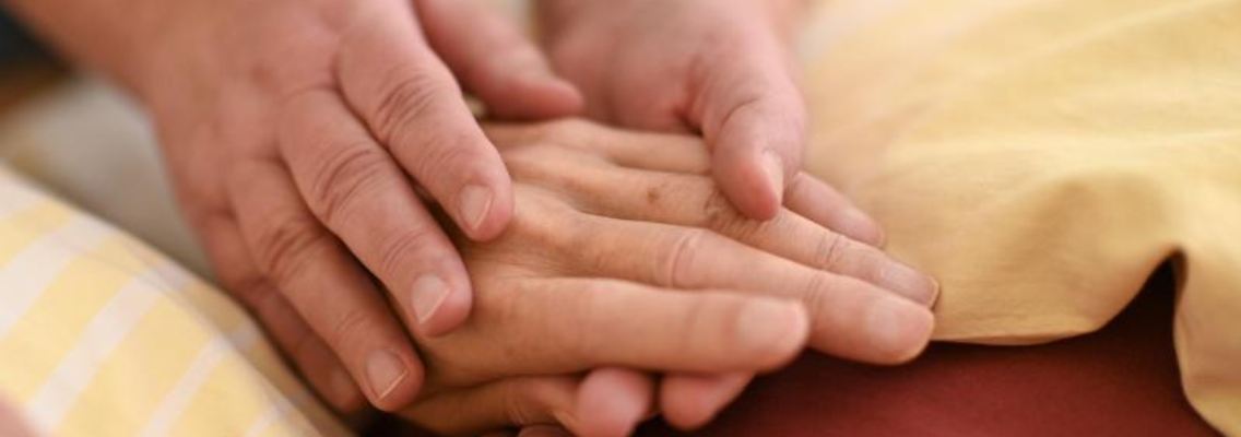 Eine Hospizmitarbeiterin hält die Hand eines todkranken Menschen. Foto: Felix Kästle/dpa/Symbolbild