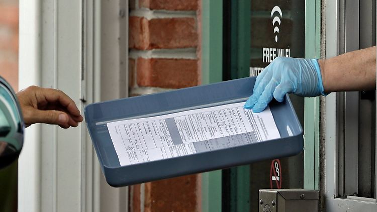 In Tampa im US-Bundesstaat Florida werden durch ein Fenster Formulare zur Arbeitslosigkeit weitergereicht. 