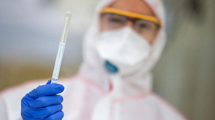 Ein Mitarbeiter hält in einem Abstrichzentrum einen Coronatest-Abstrich in der Hand.