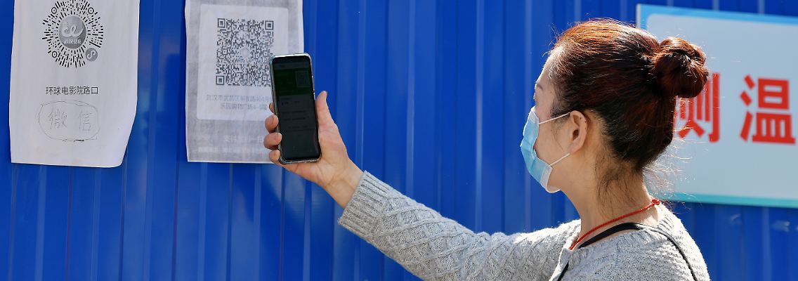Eine Anwohnerin scannt einen Gesundheits-QR-Code am Eingang zu ihrer Gemeinde in Wuhan. Im Ursprungsort der Pandemie sind nach zweieinhalb Monaten Abriegelung die Bewegungsbeschränkungen für die elf Millionen Bewohner aufgehoben - sofern sie in einer Corona-Gesundheits-App auf ihrem Handy einen grünen Code nachweisen können.