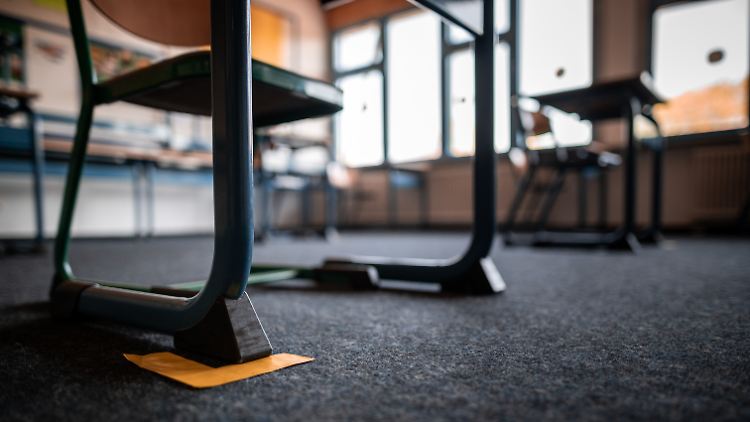 Zettel am Boden markieren die einzuhaltenden Abstände in einem Klassenzimmer in Nordrhein-Westfalen.