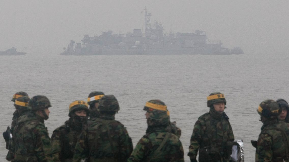 Südkoreanische Soldaten stehen auf der Insel Yeonpyeong. Im Hintergrund liegt ein südkoreanisches Kriegsschiff vor Anker.