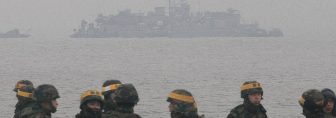 Südkoreanische Soldaten stehen auf der Insel Yeonpyeong. Im Hintergrund liegt ein südkoreanisches Kriegsschiff vor Anker.