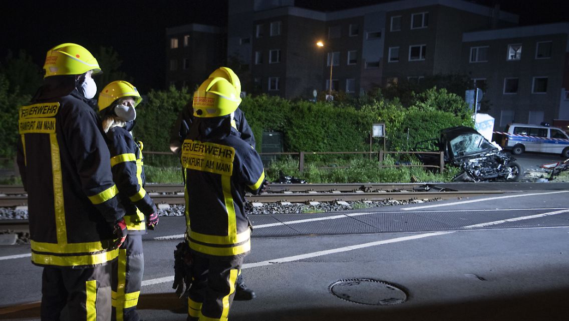 Feuerwehrleute begutachten an der Unfallstelle die Überreste des Autos.
