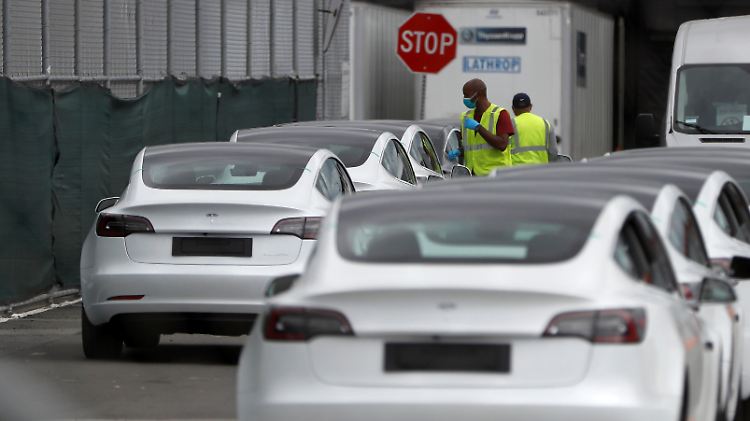 Zwei Mitarbeiter überprüfen eine Reihe von neuen Tesla Model 3. 