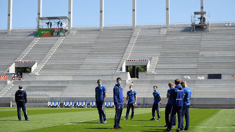 Spieler des SV Darmstadt stehen vor dem Spiel vor leeren Tribünen auf dem Rasen. 