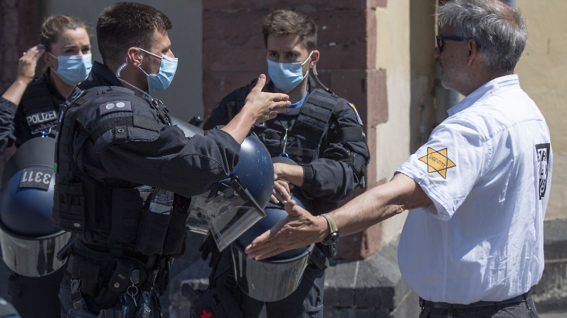 "Ungeimpft" steht auf dem einem David-Stern nachempfundenen Sticker am Arm eines Mannes, der versucht hatte, sich unter die Teilnehmer einer Demonstration zu mischen, die sich auch gegen Verschwörungstheorien zum Corona-Virus wendet.