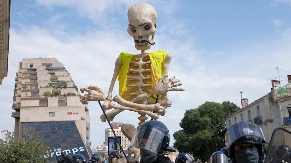 Polizisten in Montpellier nehmen einen Puppenspieler fest, der ein Skelett mit gelber Weste bewegt.