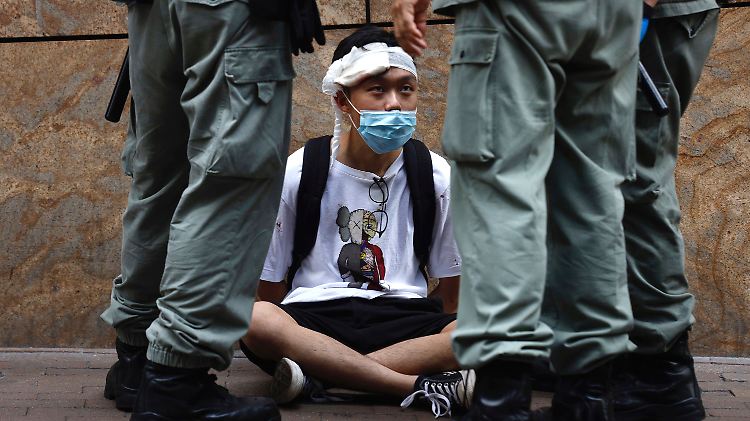 Bereitschaftspolizisten setzen in Hongkong einen Demonstranten fest.