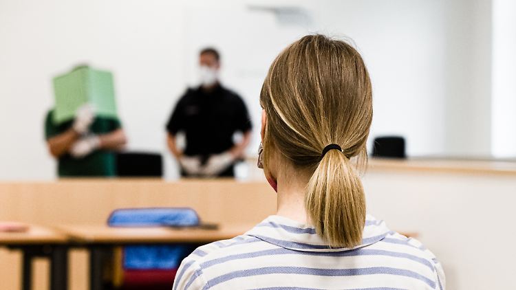 Die betroffene Frau sitzt ihrem Peiniger im Landgericht Lübeck gegenüber, dieser verdeckt sein Gesicht mit einem Aktenordner.