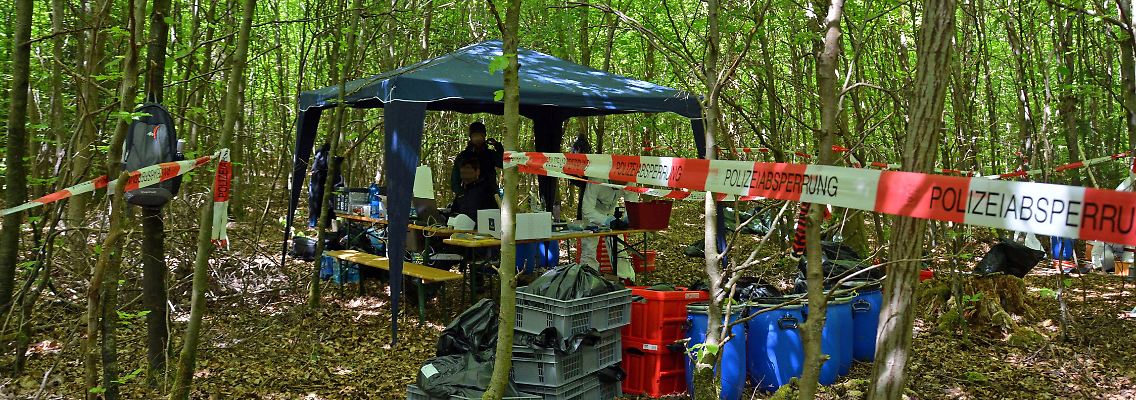 Säcke und Tonnen mit sichergestellter Erde hat die Polizei in einem abgesperrten Waldstück aufgestapelt.
