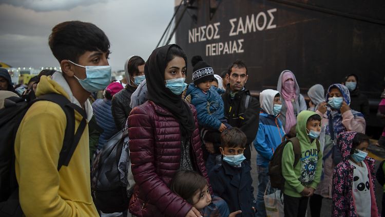 Migrantinnen und Migranten aus dem Lager Moria, die mit einem Schiff von der Insel Lesbos gekommen sind, stehen nach ihrer Ankunft im Hafen von Piräus bei Athen. 