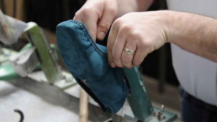 Ein Mitarbeiter des Schuhherstellers Sioux bearbeitet einen Schuhrohling auf der Leiste.  