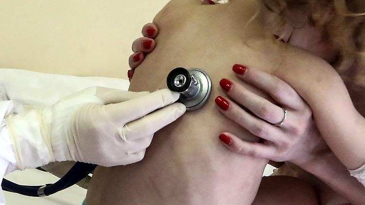 Eine Mutter hält ihr Sars-CoV-2-infiziertes Kind in einer Klinik zum Abhören hoch.  
