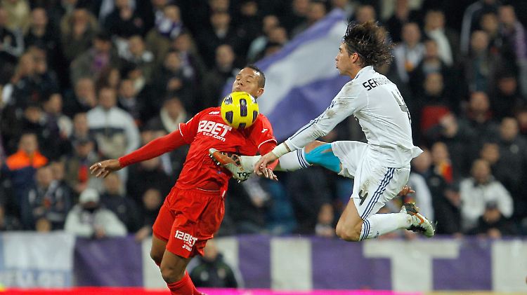 Madrids Sergio Ramos klärt artistisch gegen Sevilla-Stürmer Luis Fabiano.