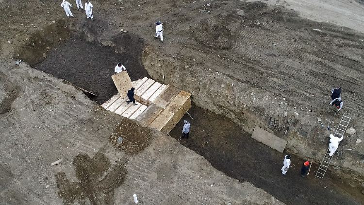 New York City: Arbeiter in Schutzanzügen vergraben im April 2020 Covid-19-Tote in einfachen Holzsärgen in einem Graben auf Hart Island in der Bronx.