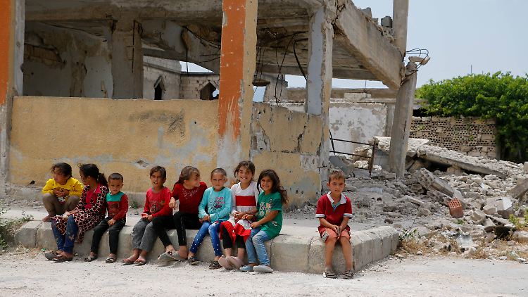 Syrische Kinder sitzen in der Region Idlib vor ihrer zerstörten Schule.
